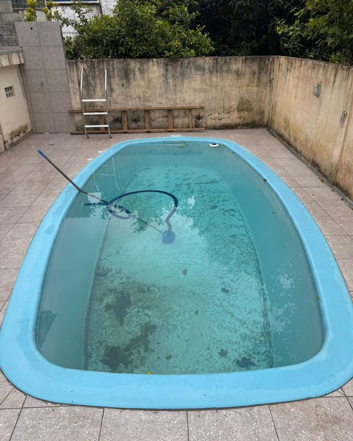 Piscina de fibra antes da limpeza, com a água turva e sujeira acumulada no fundo.