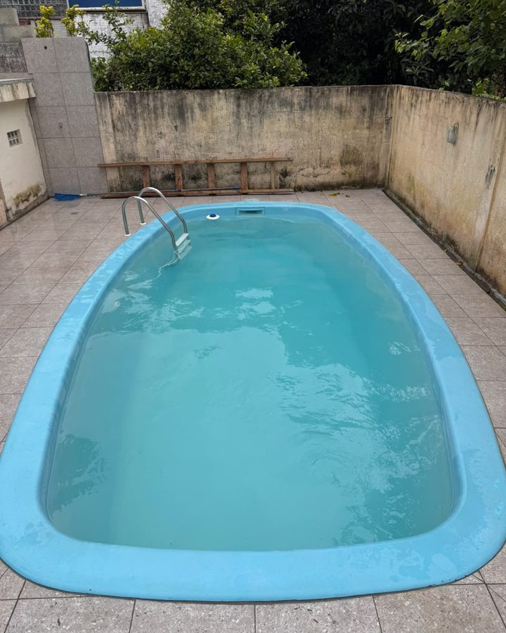 A mesma piscina de fibra depois da limpeza, com a água limpa e o fundo sem sujeira.